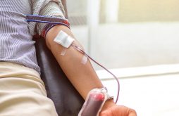 Blood donor at donation, transfusion. Close up right arm of a business man receiving blood in hospital. Healthcare and charity. Also concept image background for World blood donor day - June 14 .